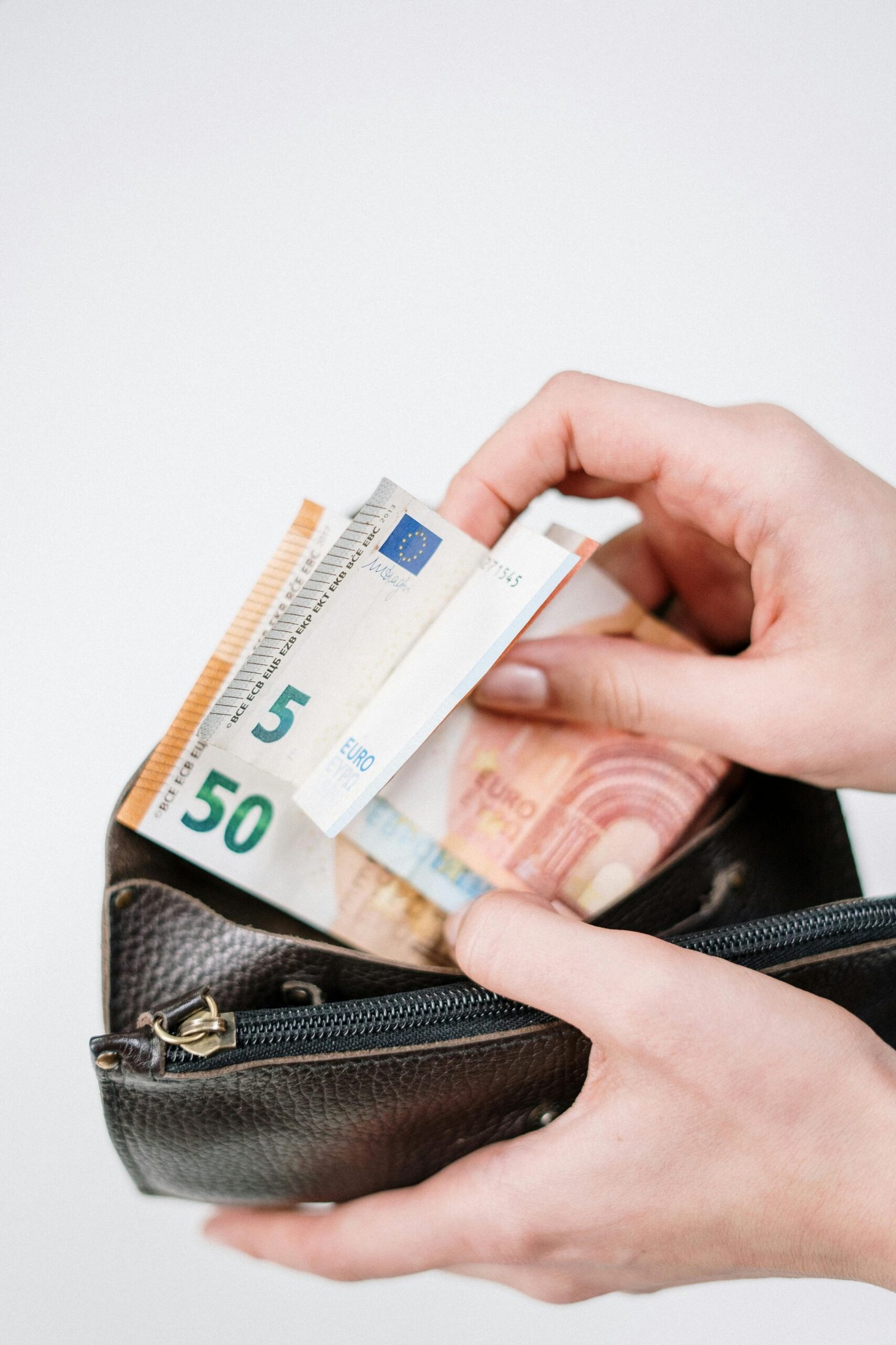 Close-up of hands with euro banknotes being placed in a wallet. Ideal for finance-related content.