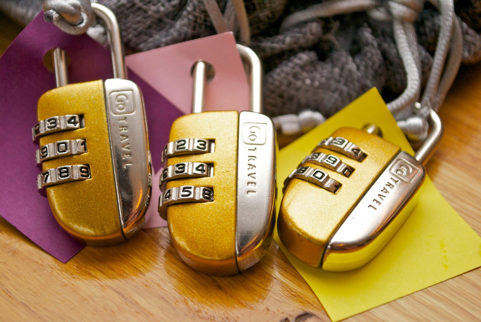 Three gold combination padlocks with colorful tags, symbolizing security and travel.