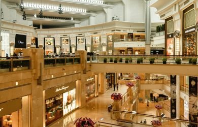 Contemporary design of big mall interior with ribbed column and decorative elements on ceiling with glowing corridors illuminated by artificial lights and signboards with inscriptions